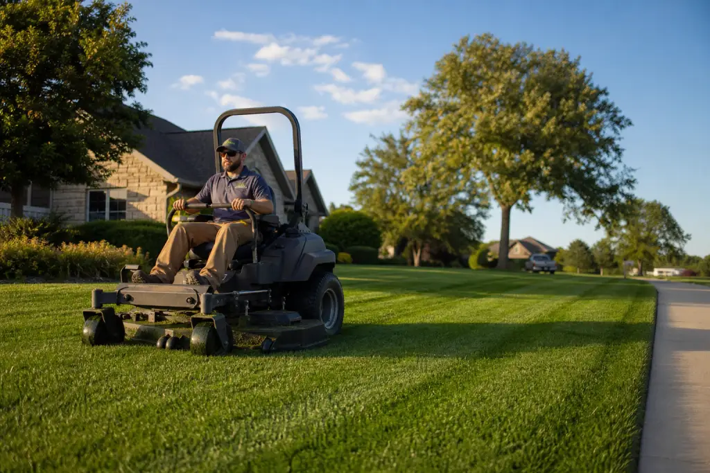 Professional lawn maintenance in Lancaster, Ohio with a lawn care technician mowing a residential property